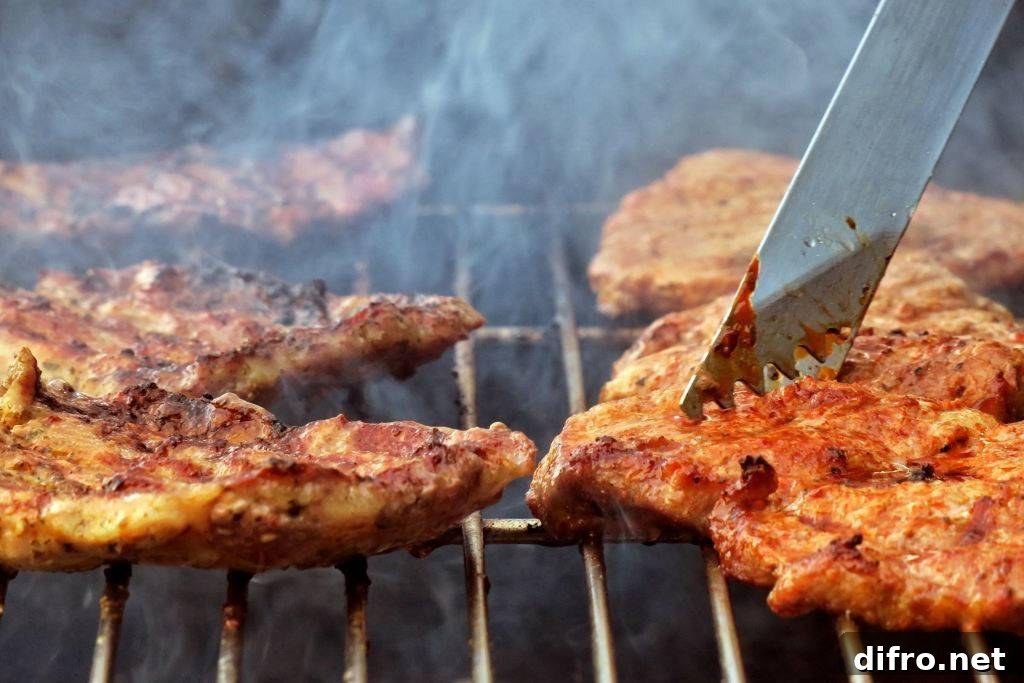 Steaks lie on a charcoal grill in a garden