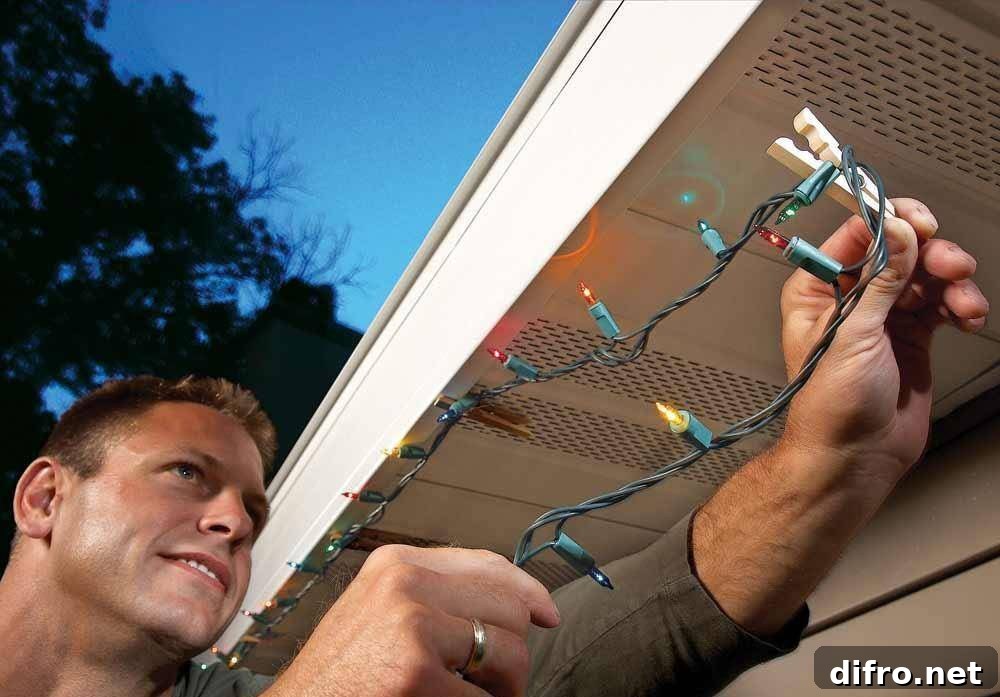 Man installing Christmas lights on underneath the house's gutter system.