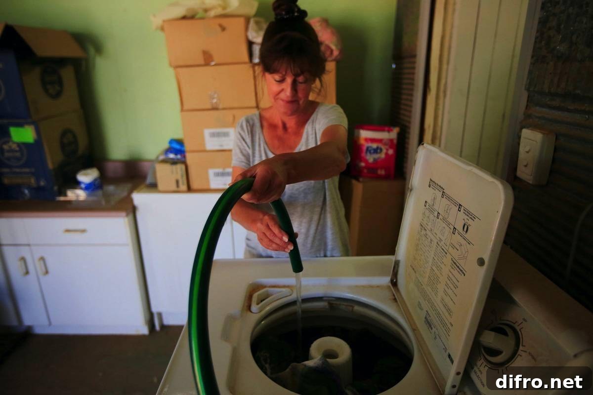 A woman fills her washing machine manually with a hose.