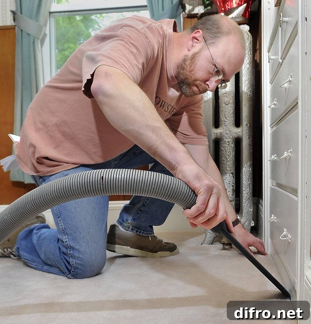 A man steam cleans a corner of a carpet.