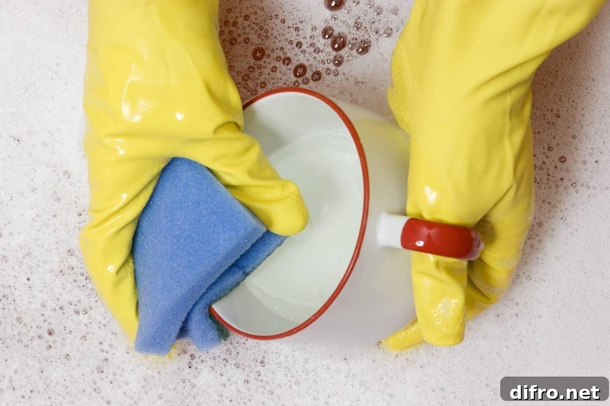 A person washes a mug with a sponge.