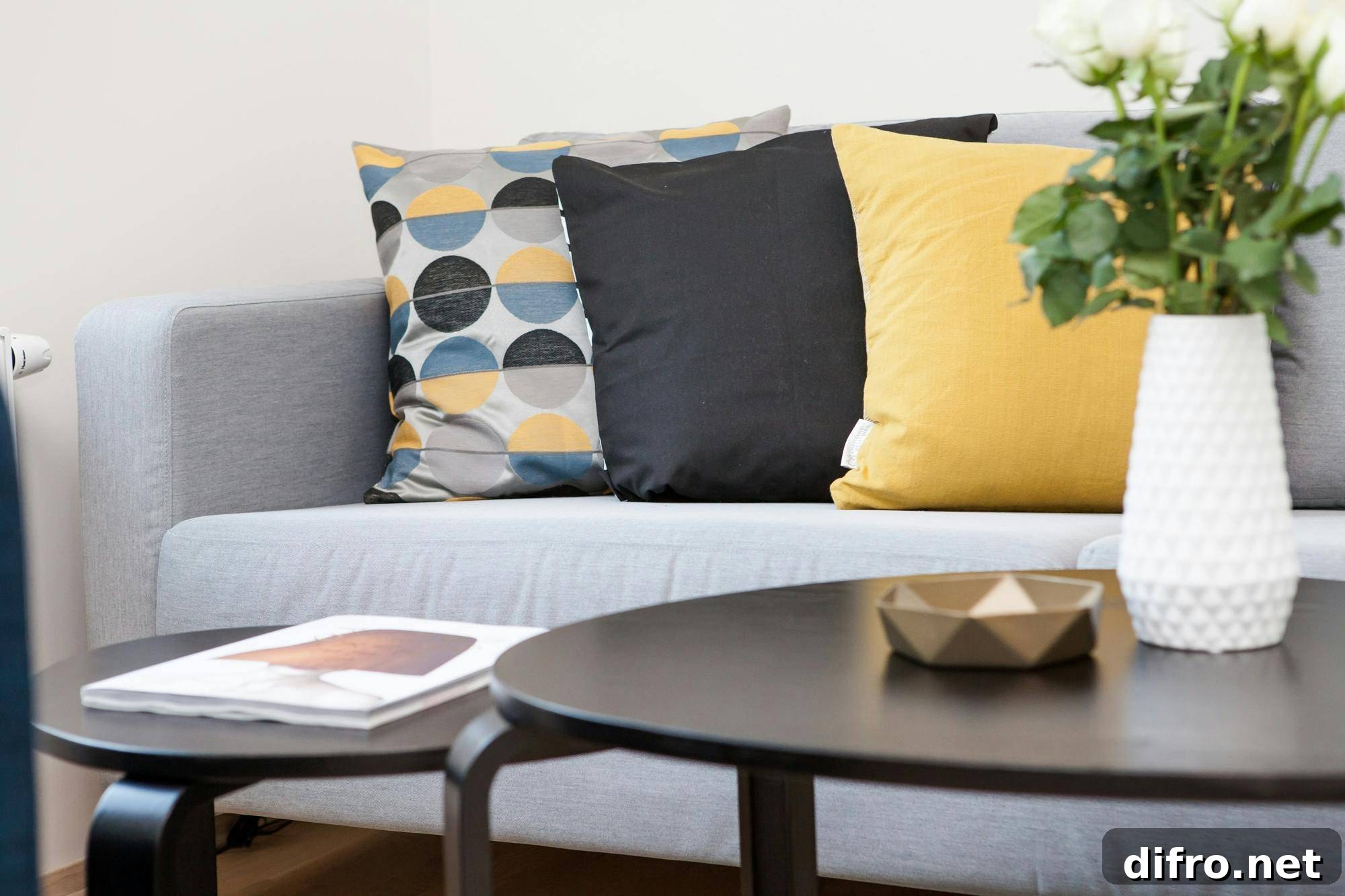 Three throw pillows on a grey couch behind a coffee table.