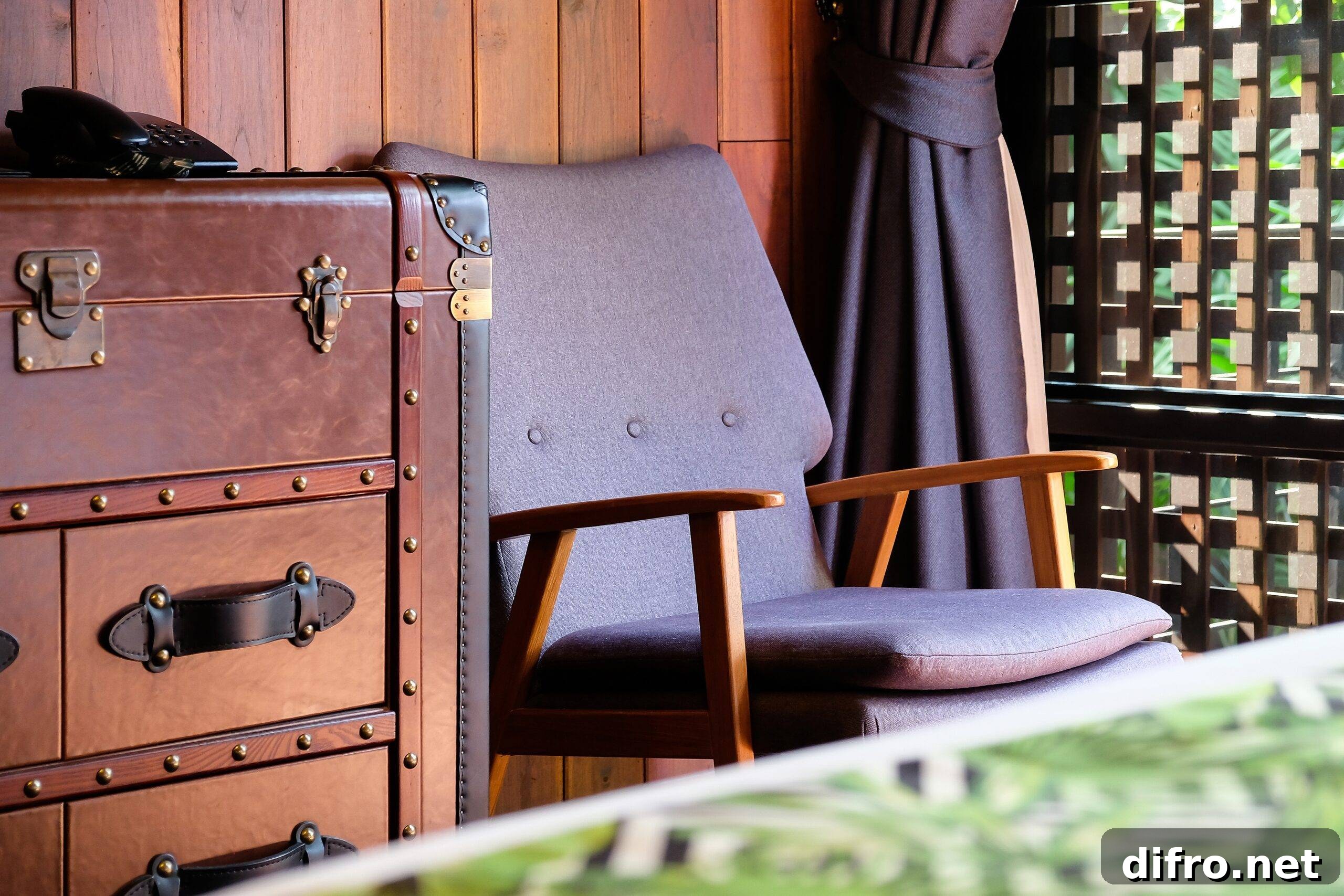 A close shot of some vintage furniture, a mid-century-modern chair and a more antique trunk-style dresser.