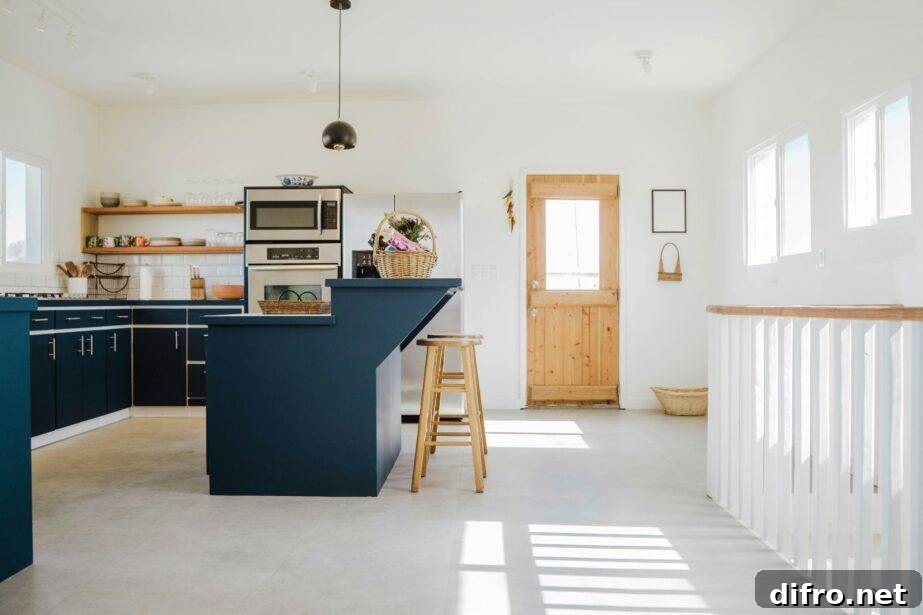 A large white kitchen with a navy blue island and cabinets.