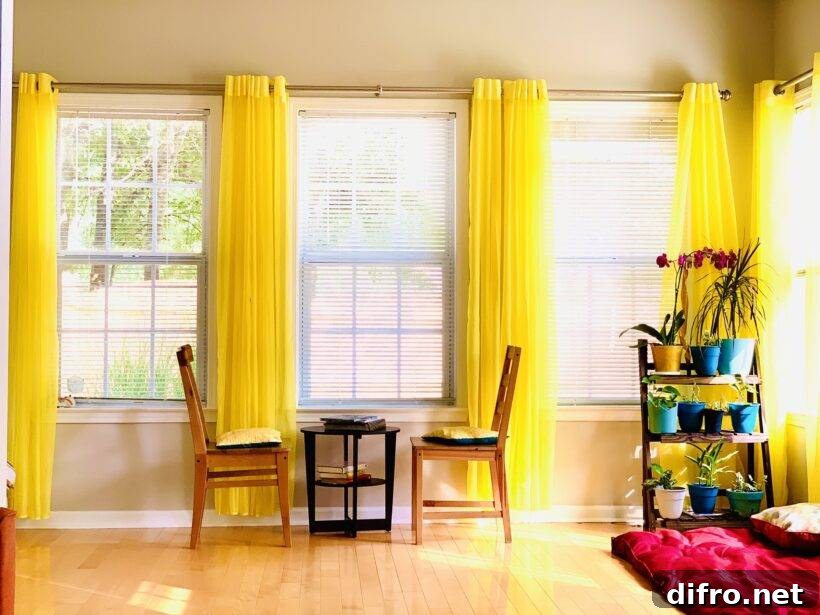 A sunroom with bright yellow curtains on each side of each large window.