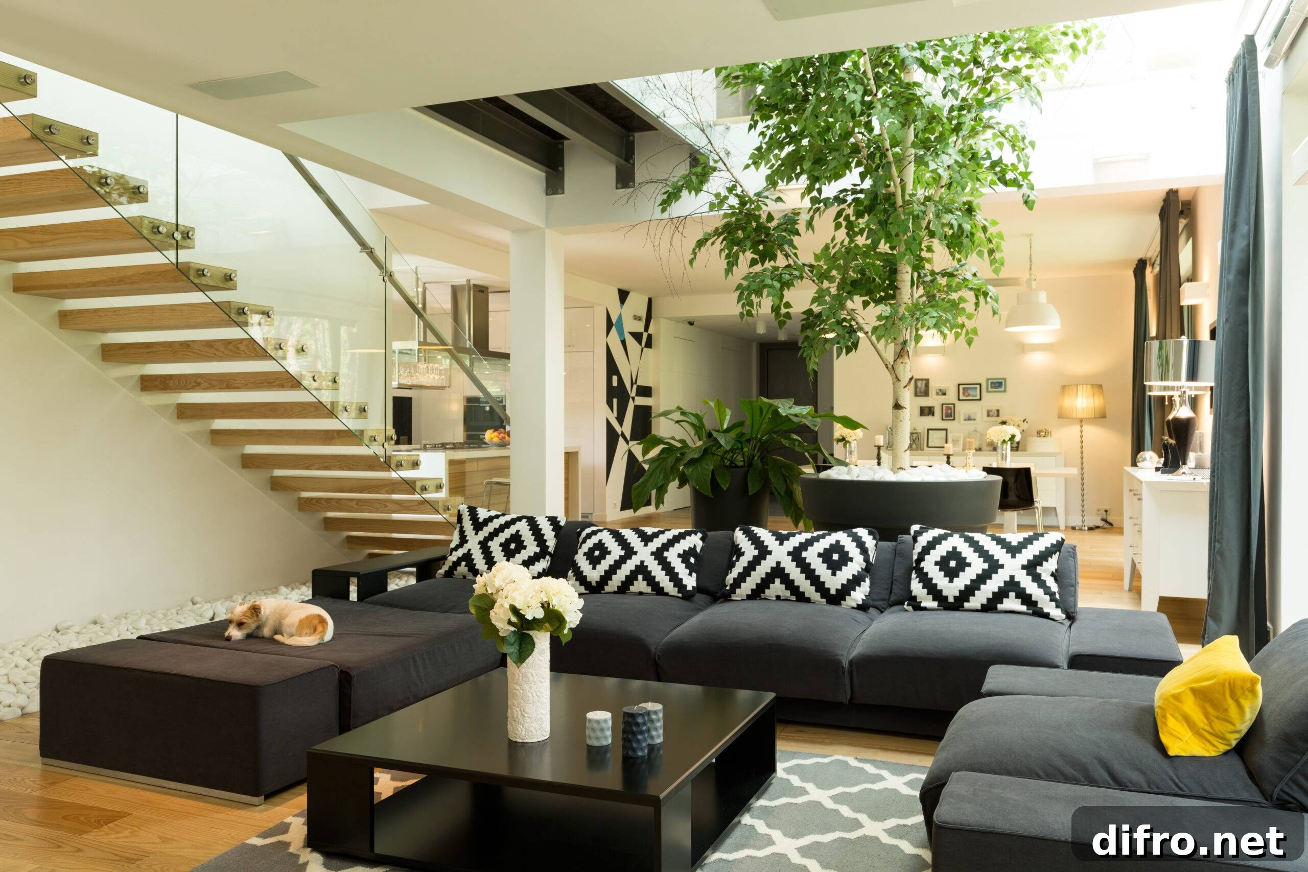 Living room with black sofa, patterned pillows and coffee table open to the staircase