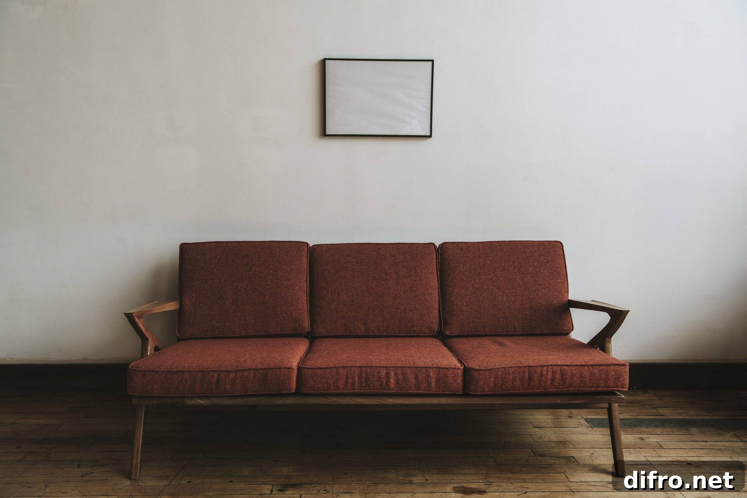 A red mid-century modern couch against a blank wall.