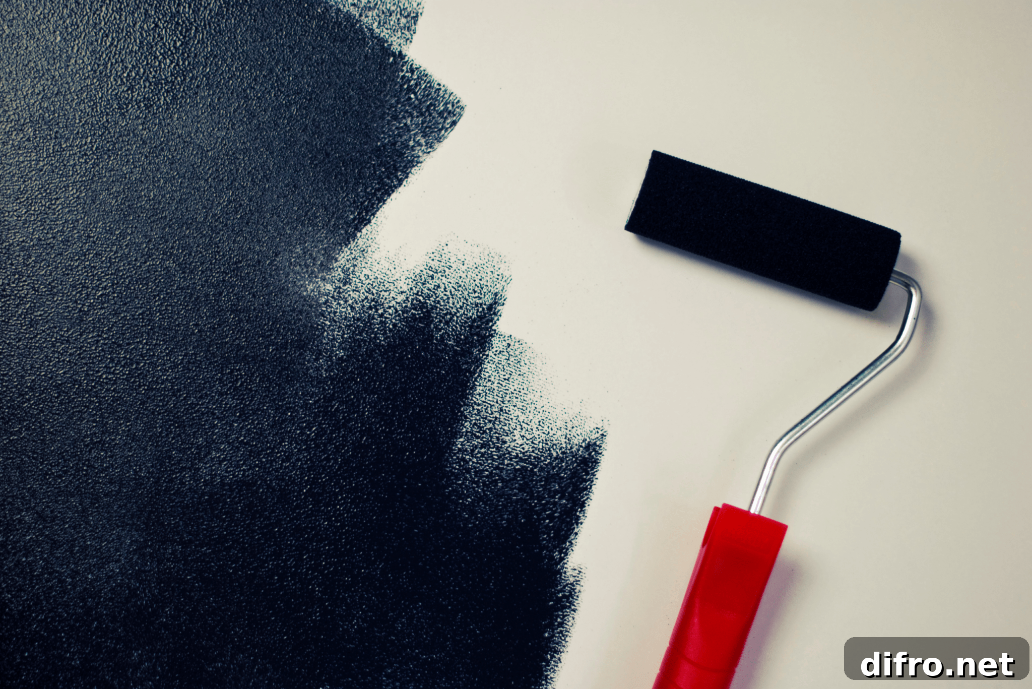 Why Add Sand to Paint: Benefits, Uses, and Tips 6 A navy blue paint roller next to a half-painted wall.