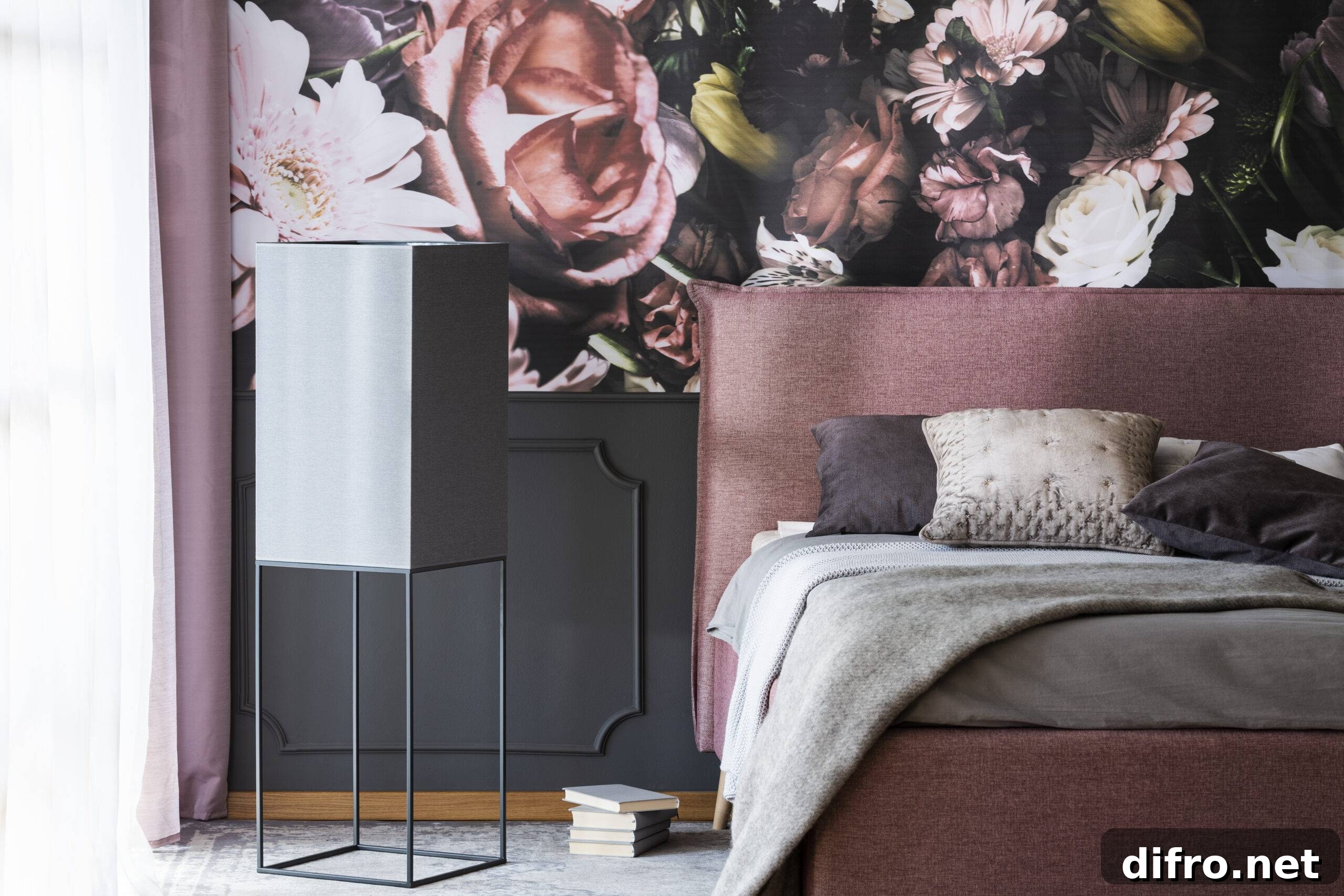 Grey pillows and bedding on bed in pink bedroom interior with flower wallpaper. Real photo