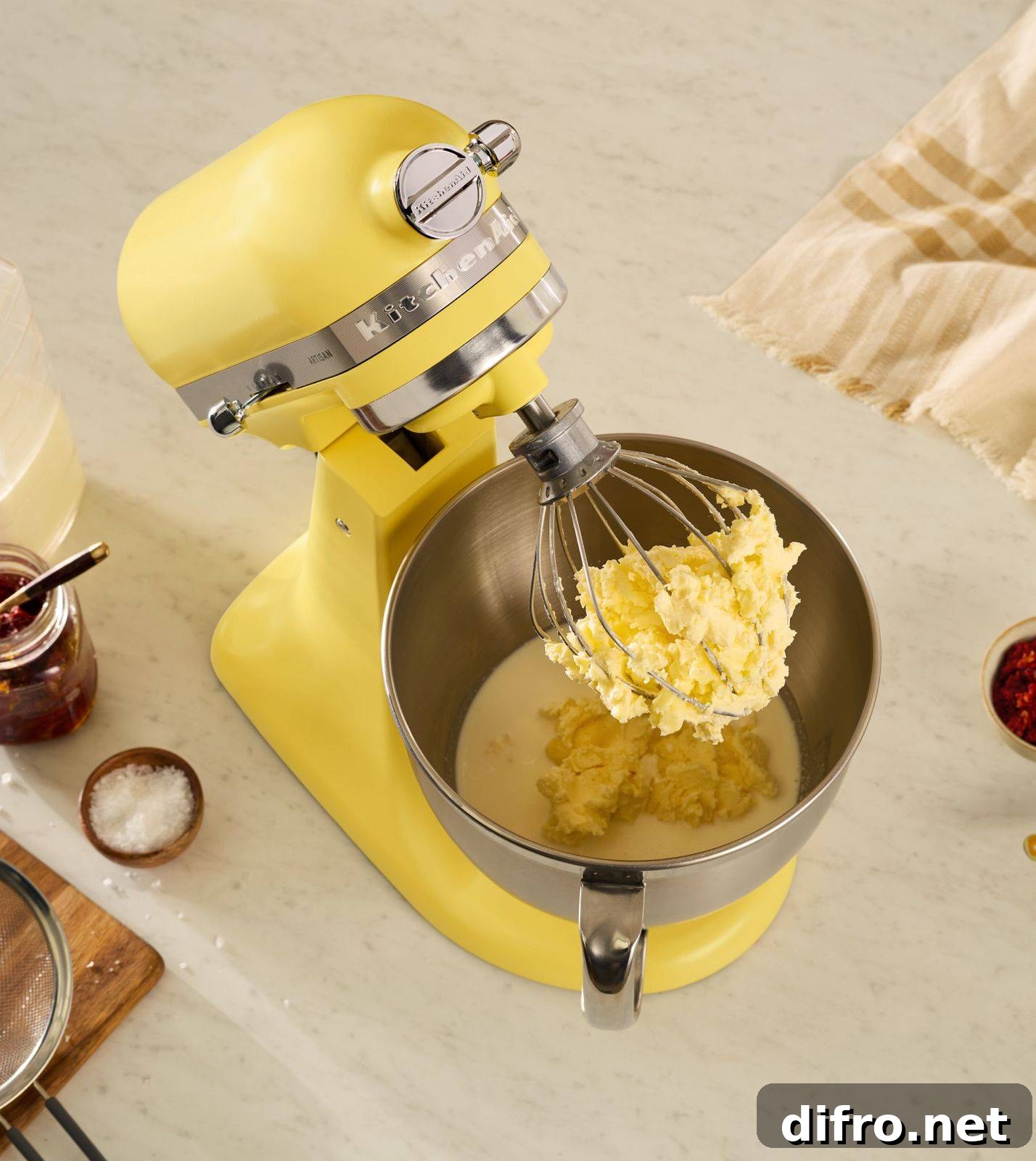 An above angle shot of a yellow kitchenaid mixer in the middle of churning some butter and buttermilk.