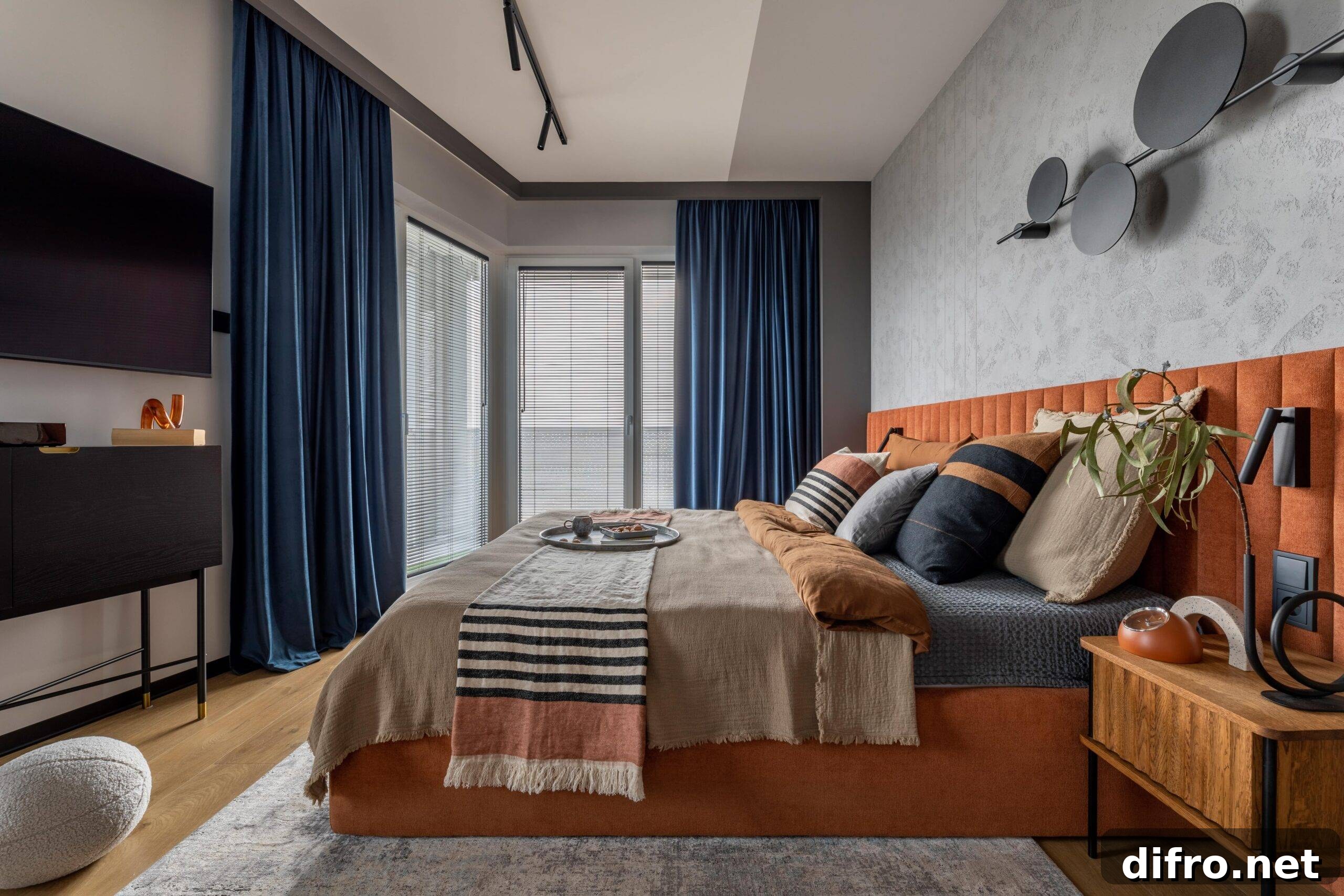 A bedroom with a large bed decorated with orange and blue linens.