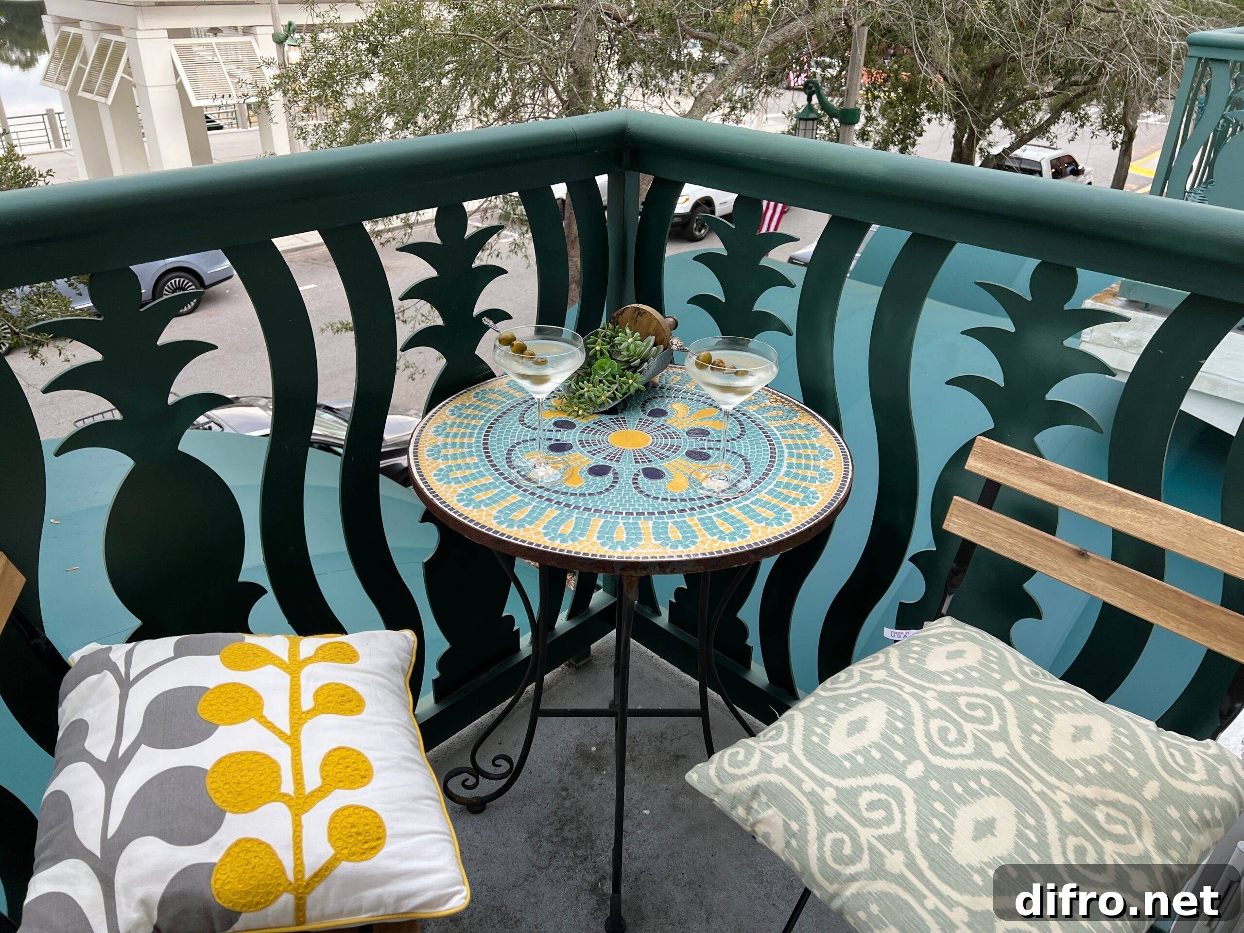 A small table and two chairs with colorful cushions on a balcony.