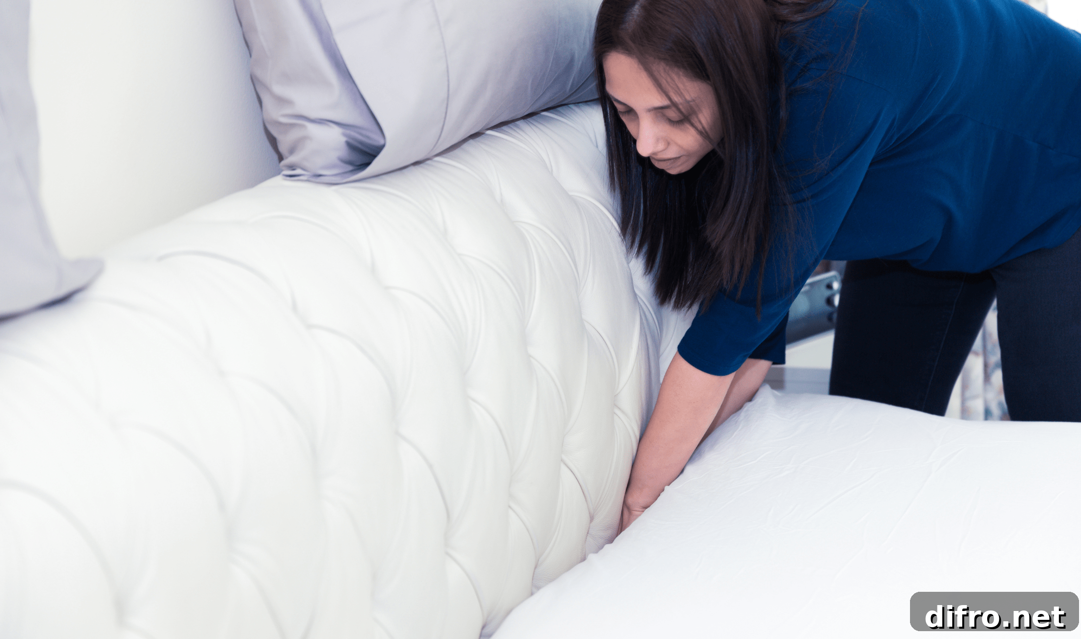 A woman tucking her flat sheet into her mattress.