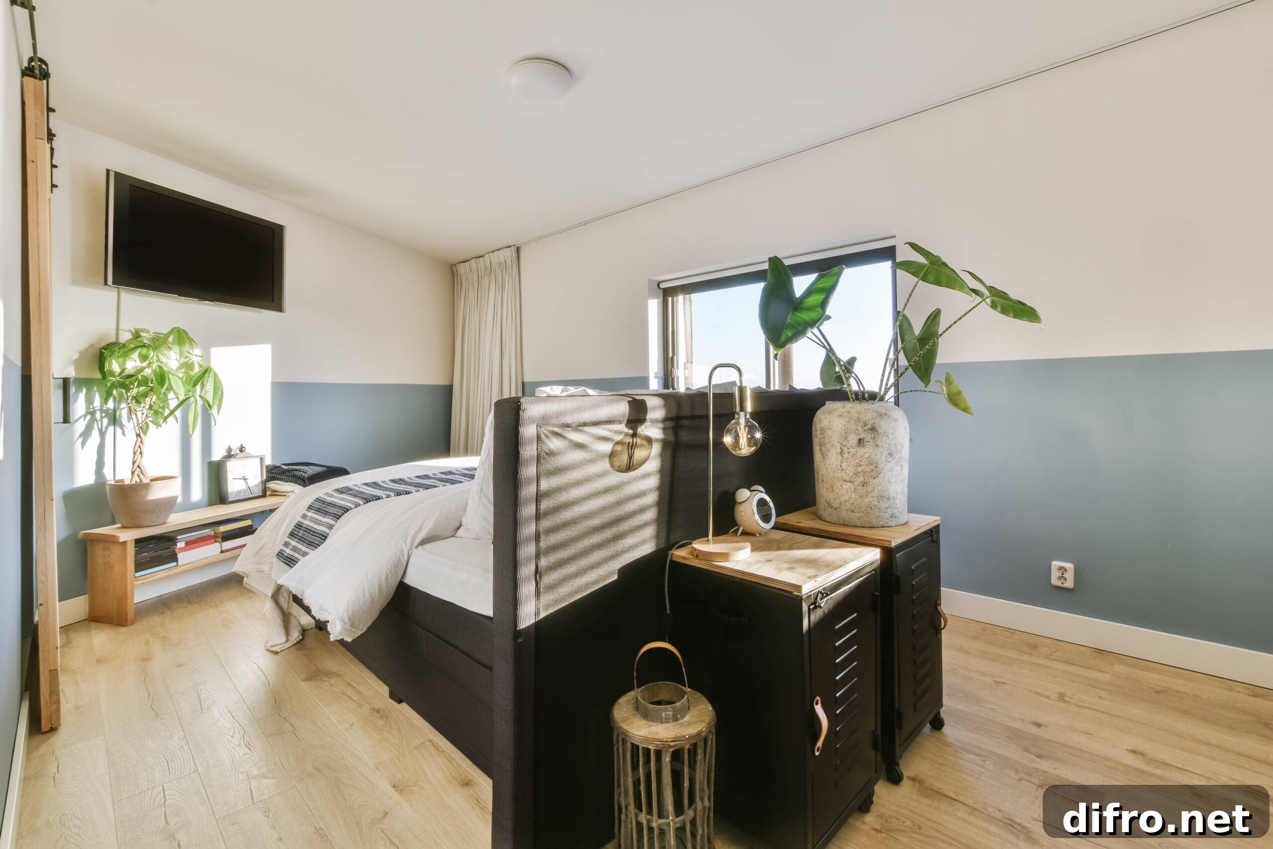Luxury bed with soft pillows and blanket located against white wall in stylish bedroom